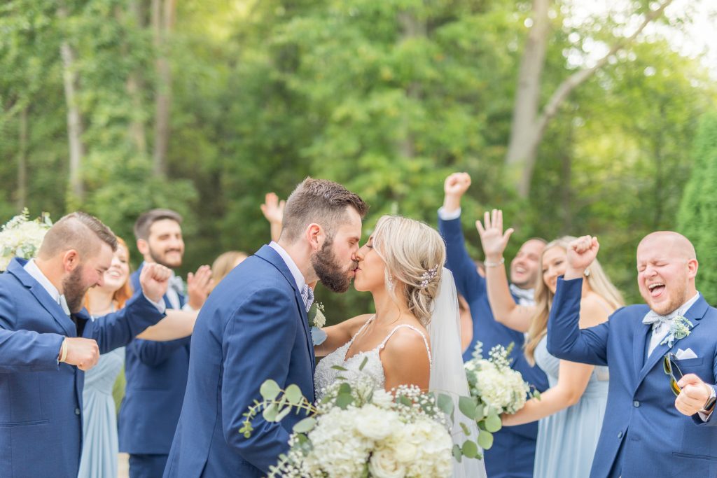 Samantha and Matthew Simko's Hudson, Ohio summer wedding at Highfield Event Center photographed by Bree Thompson Photography serving San Diego Luxury Wedding Photographer. Bridal Party kissing photo with bridesmaids and groomsmen cheering.