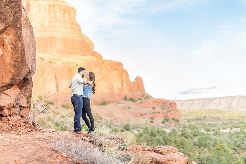 Couple climbing Bell Rock in Sedona with engagement ring during golden hour.