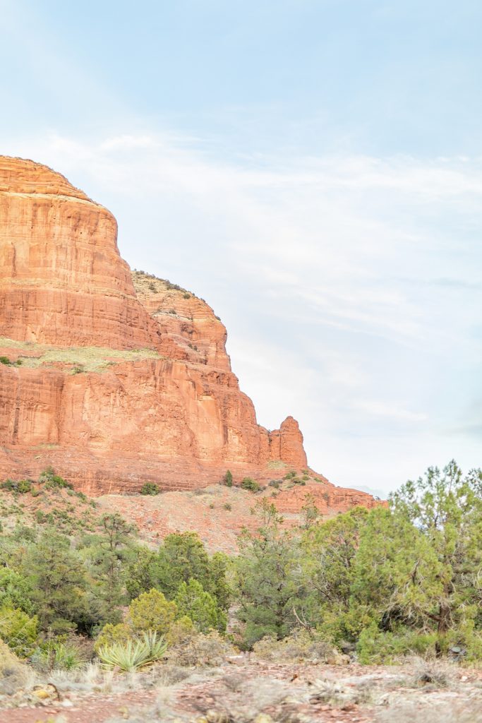 Couple climbing Bell Rock in Sedona with engagement ring during golden hour.