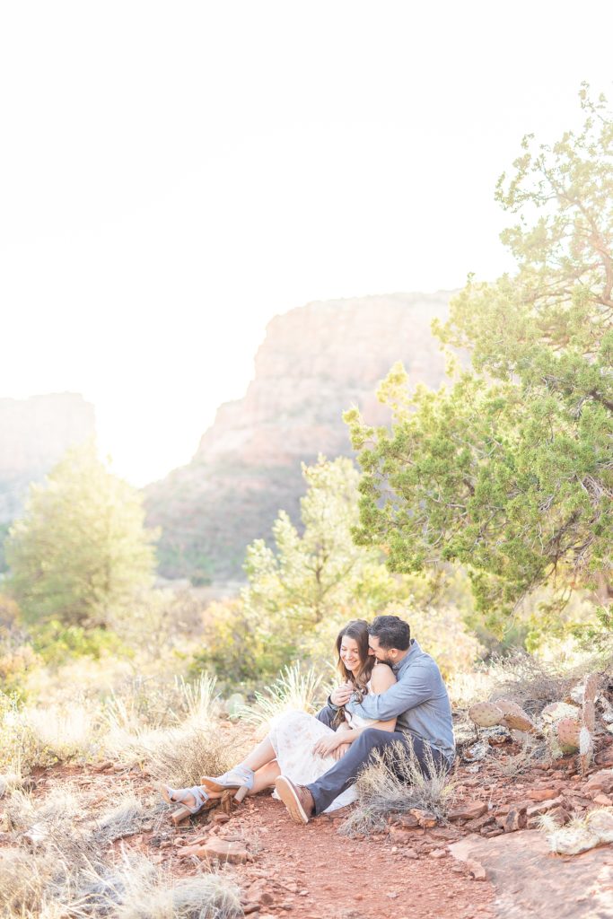 Couple laughing under tree on Bell Rock mountaintop.