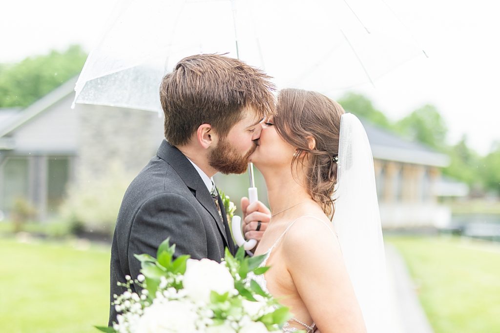 Bride and groom kissing with flower bouquet in the rain by Sherr Weddings based in San Diego, California.