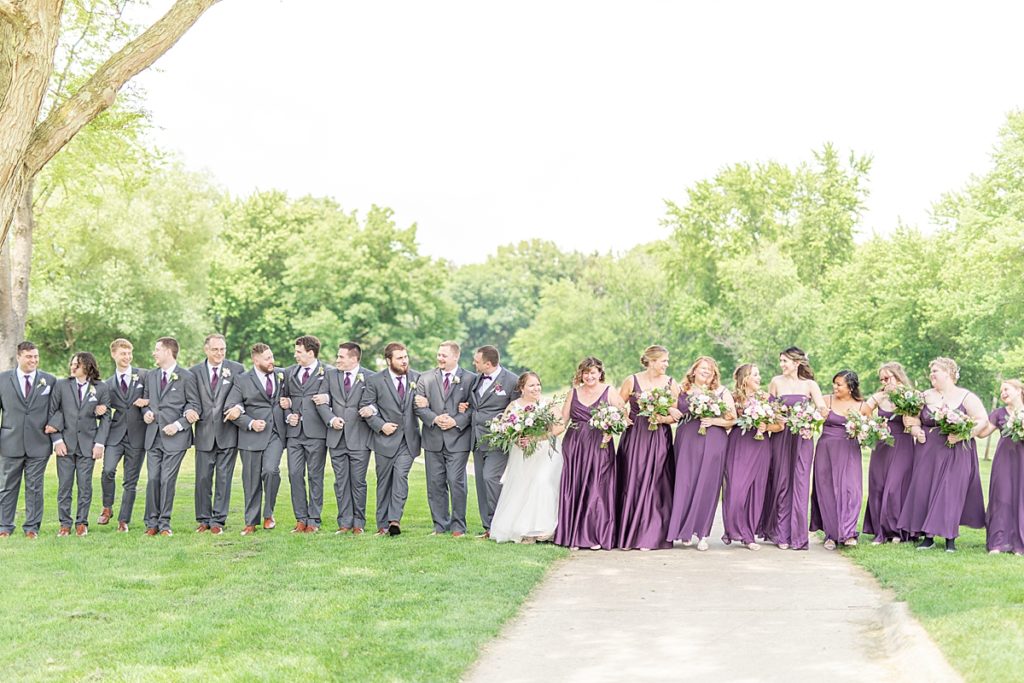 Wedding party with bridesmaids and groomsmen cheering for bride and groom with rose petals.