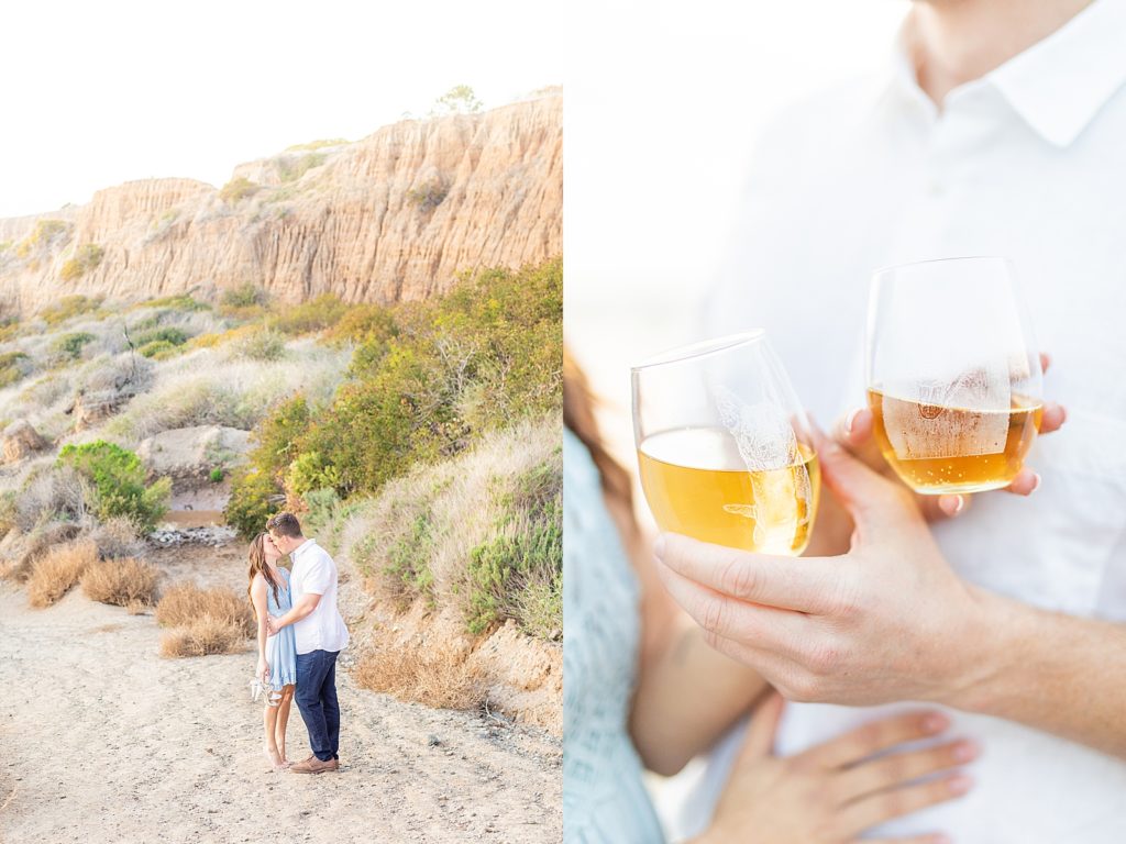 Couple holding champagne and kissing by bluffs and mountains.