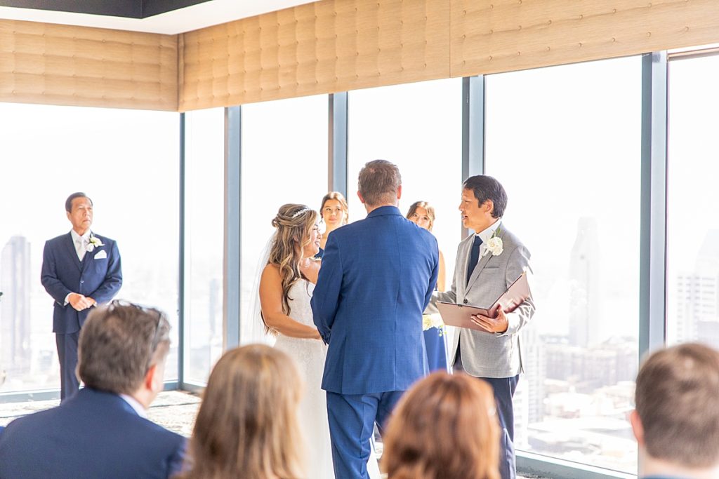 Bride and groom sharing vows during wedding ceremony in skyscraper.