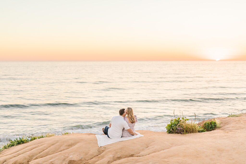 Couple kissing overlooking sunset over the ocean by Sherr Weddings.