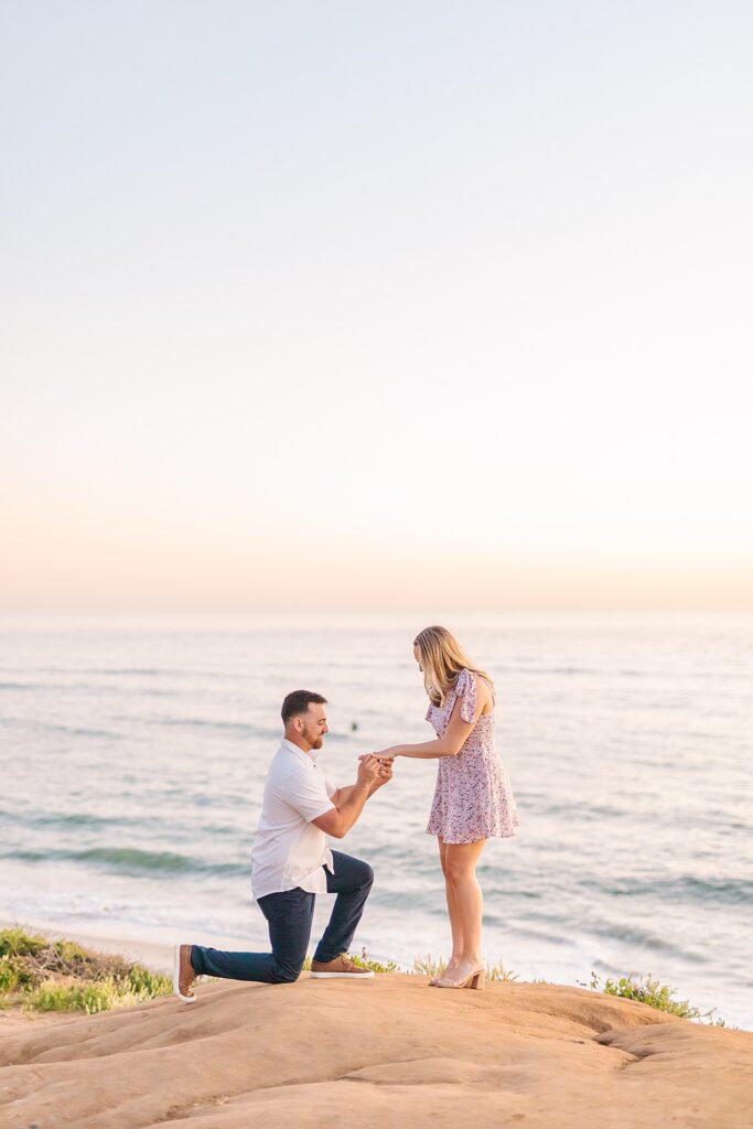 Engagement proposal putting on ring at Carlsbad Cliffs at sunset.