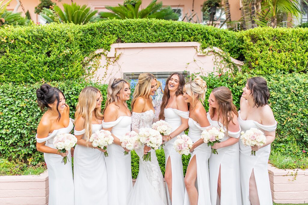 The bride and her bridesmaids dressed in white laughing together.