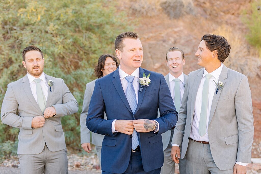 Groom walking with groomsmen in front of Arizona's red rocks.