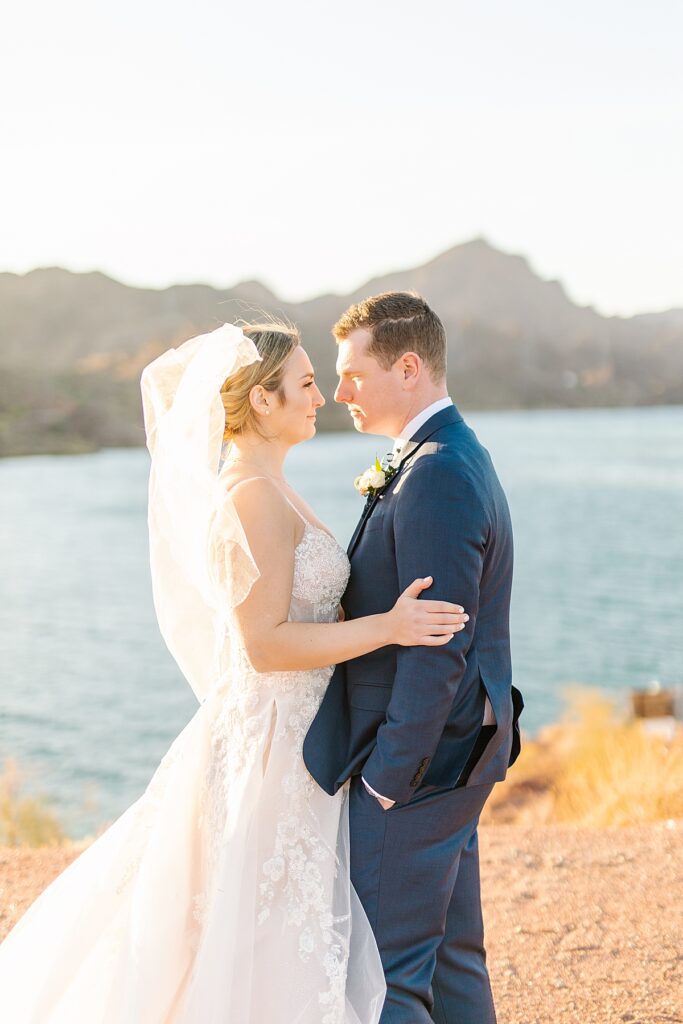 Bride and groom smiling and taking sunset portraits together overlooking the Colorado River in Arizona.