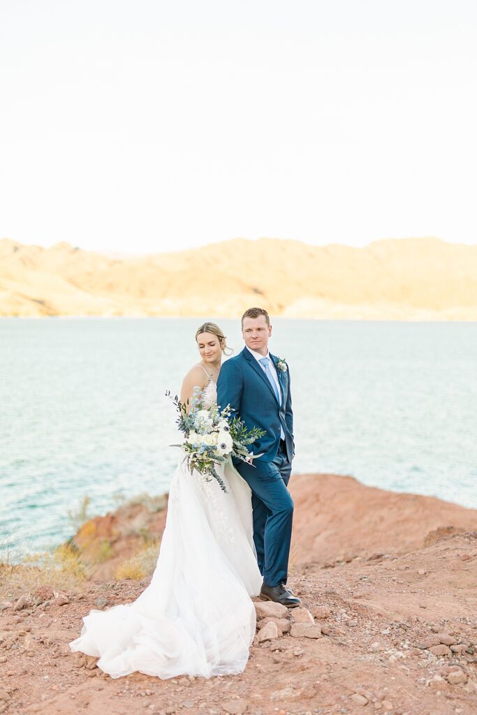 Bride and groom smiling and taking sunset portraits together overlooking the Colorado River in Arizona.