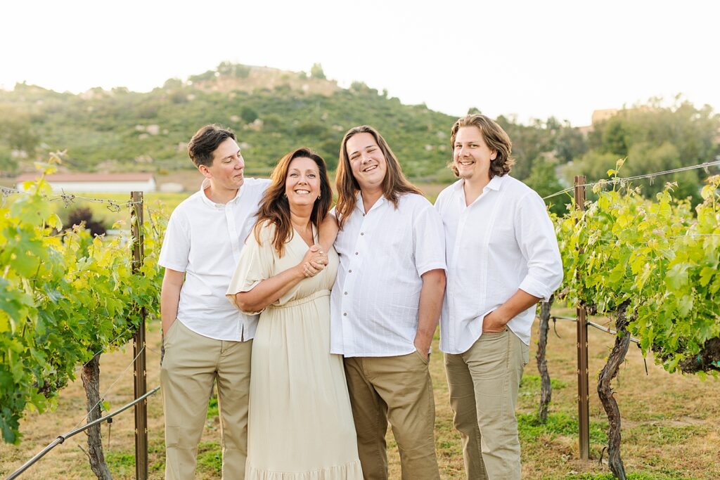 Mother and sons smiling together in backyard vineyard during extended family photography session.