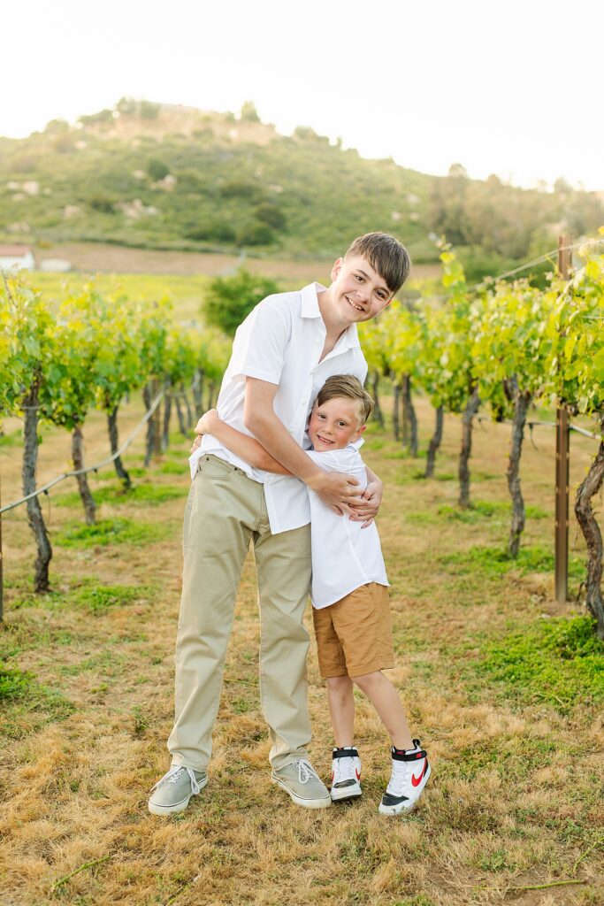 Brothers hugging in vineyard at private estate in Murrieta, California.