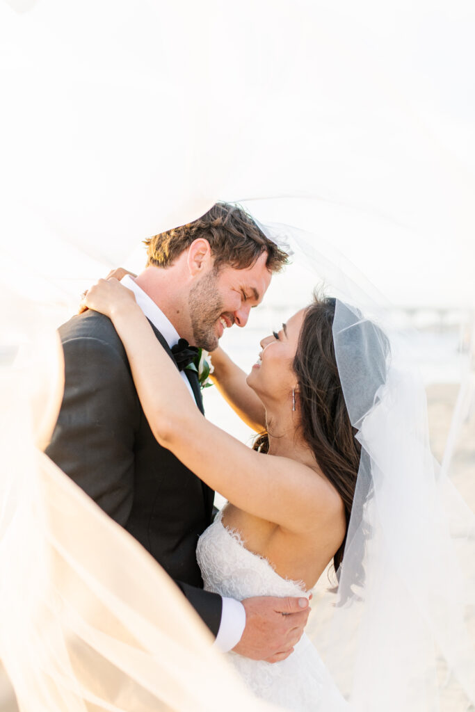 Posed image of bride and groom smiling and holding one another at Scripps Wedding Venue in La Jolla, California.