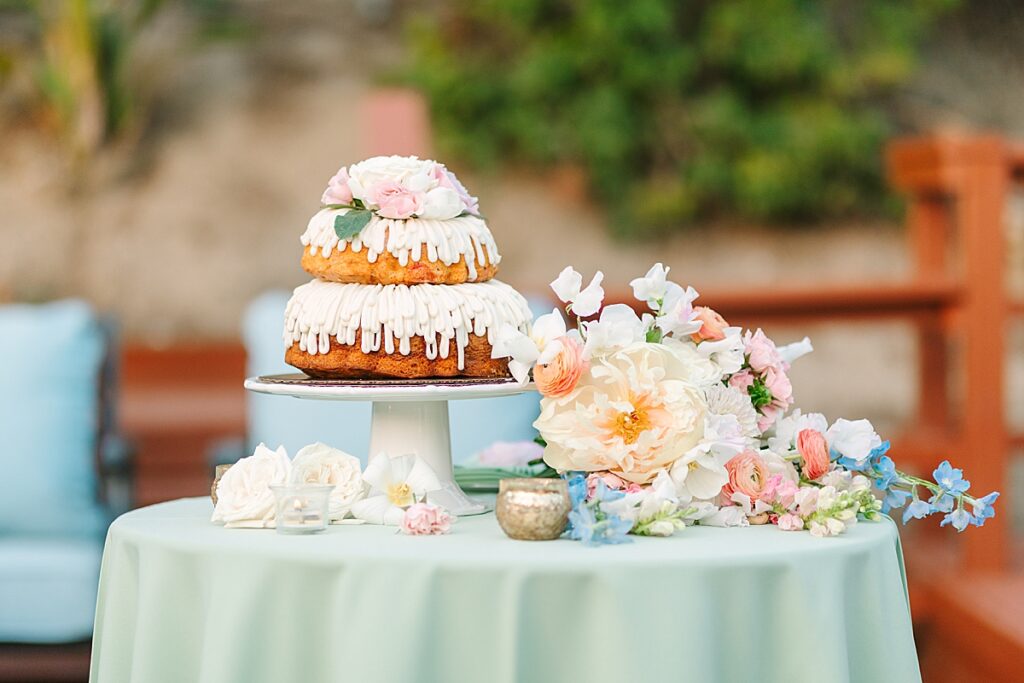 Wedding bundt two-tier cake adorned with florals on a green tablecloth covered table at private residence.