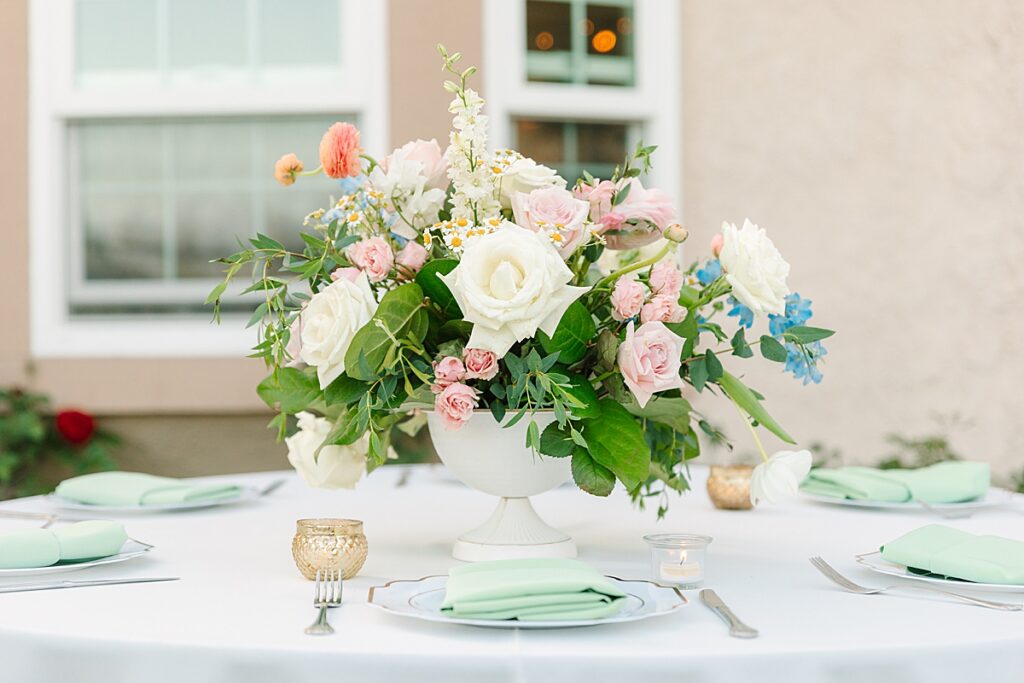 Peach, blush, and blue floral centerpiece on wedding reception table at a private residence in Orange County.