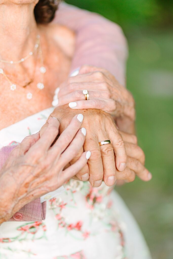 Bride and groom holding hands during their couple portraits on their wedding day, showing off their rings.