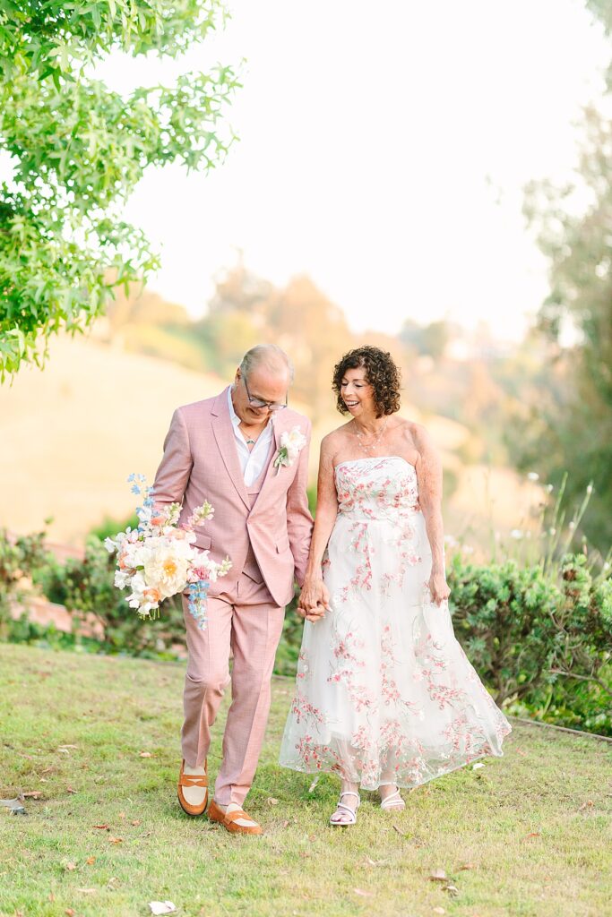 Bride and groom walking hand in hand in their front garden at their private residence wedding in Laguna Hills, California.