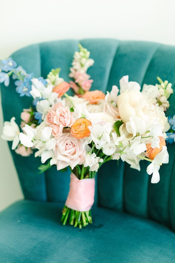 Peach, blush, and blue bridal bouquet sitting on blue chair in Laguna Hills, California.
