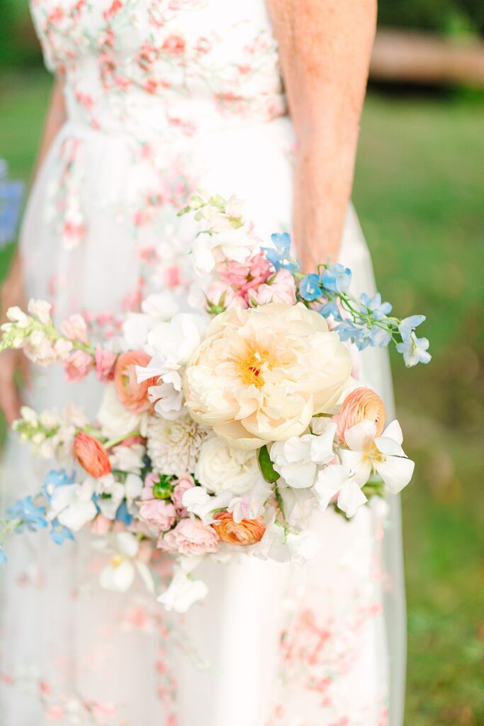Bride holding peach, pink, and blue bouquet in her private residence garden in Laguna Hills, California.