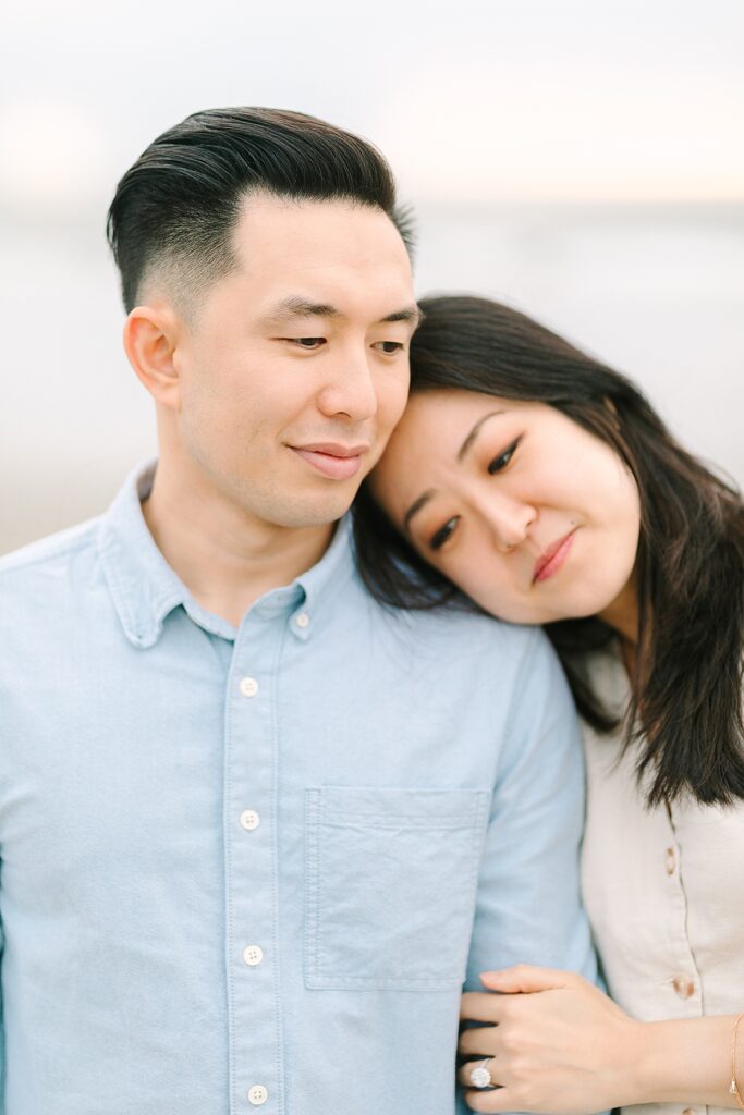 Engaged couple sharing a quiet moment on the cliffs with the ocean waves and sunset in the background.