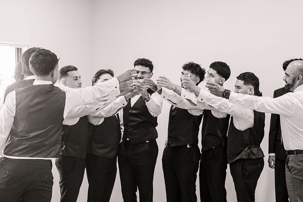 Guys cheering to the groom on his wedding day with shots in the getting ready suite.