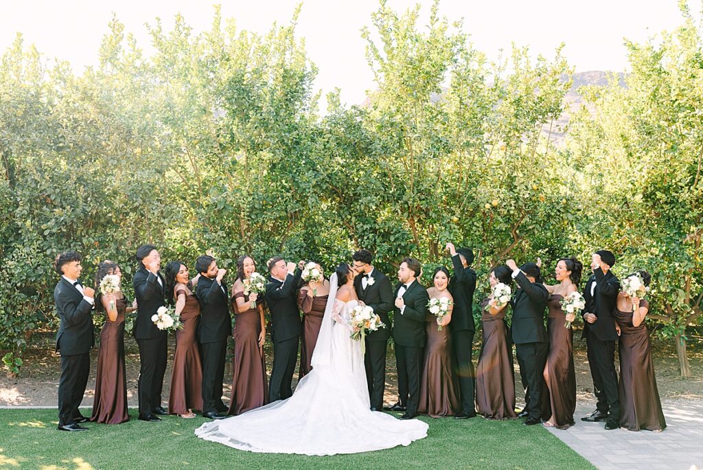 Wedding party dressed in brown and black, cheering on the bride and groom in Escondido.