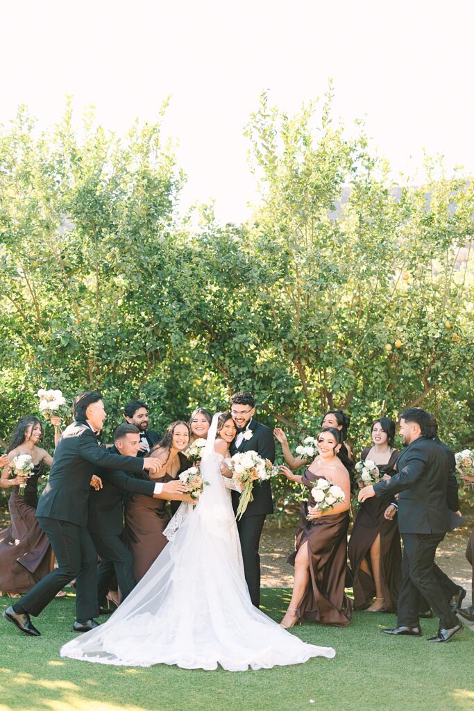 Wedding party running at the bride and groom while they smile at Rancho Guejito Vineyard in Escondido.
